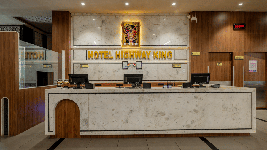 A front desk area featuring a long marble counter, computer screens, and wall branding at Hotel Highway King, Harmada.