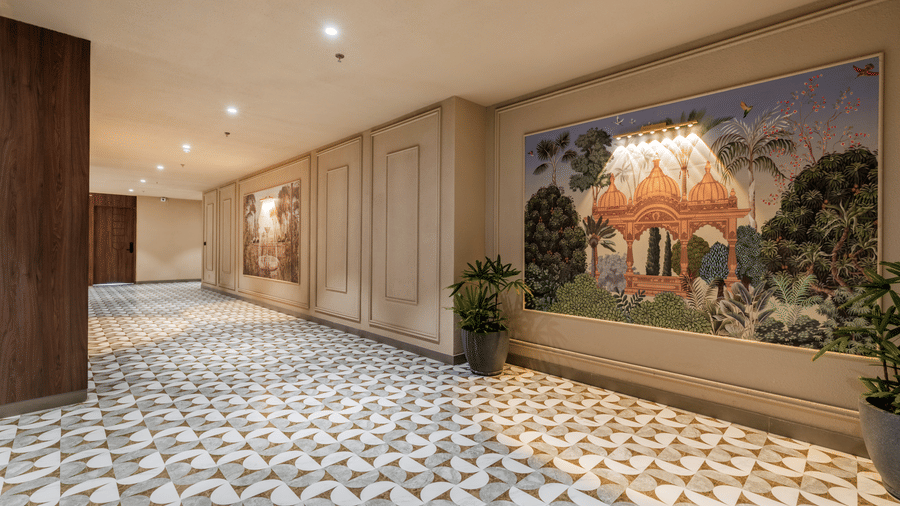 A wall section showing a 3 part traditional mural, 2 potted plants, and patterned flooring at Hotel Highway King, Harmada.
