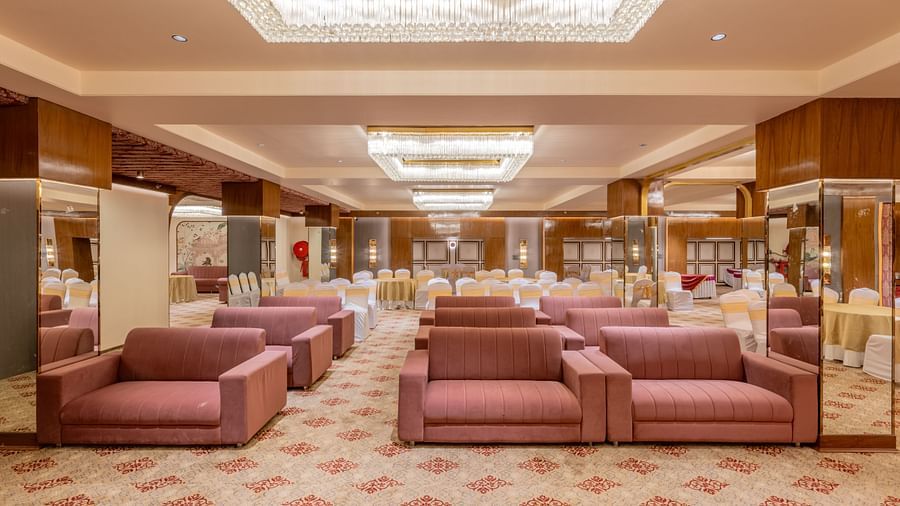 Maroon sofas arranged in a banquet hall with bright ceiling lights above at Hotel Highway King, Jaipur.