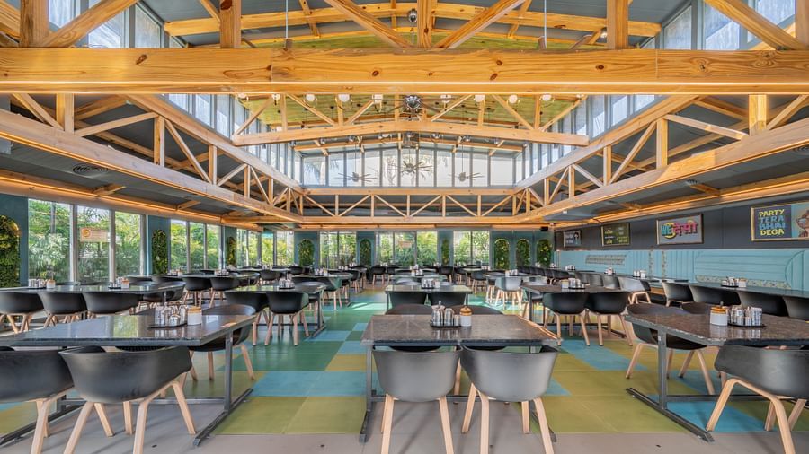 Wide view of restaurant with exposed yellow beams and black seating at Hotel Highway King, Jaipur.