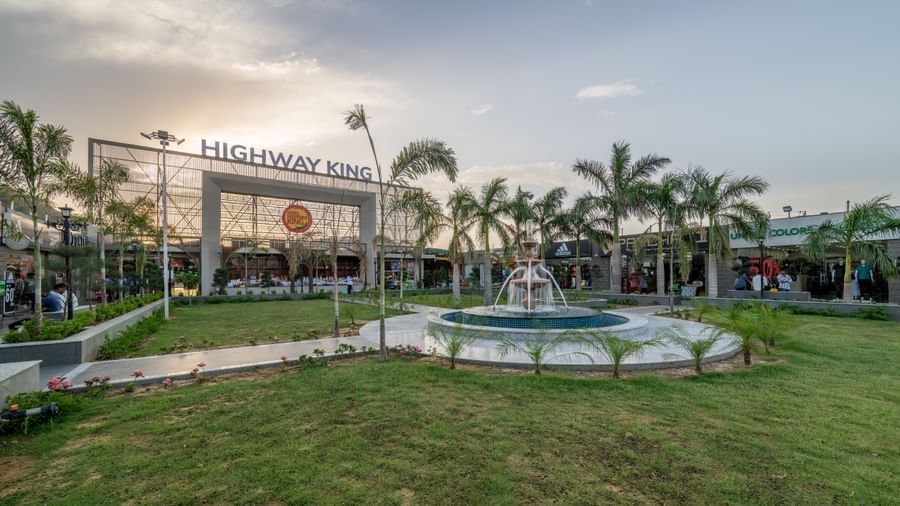 Exterior view of Hotel Highway King, Neelka against a cloudy sky, featuring the lawn area with a water fountain.