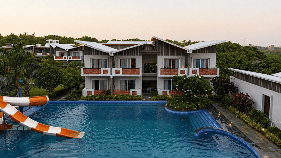A swimming pool at Hotel Sonar Bangla, Mayapur, featuring a water slide structure, steps, and accommodation balconies.