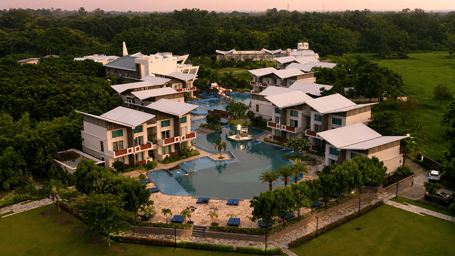A bird eye view of Hotel Sonar Bangla, Mayapur, featuring a central swimming pool, guest room blocks, and surrounding trees.