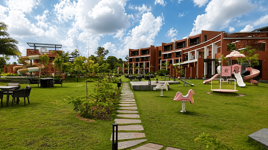 A children play park at Hotel Sonar Bangla, Susunia featuring swings, slides, spring riders, stone pathways, and garden lawns.