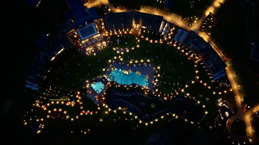 An aerial night shot of Hotel Sonar Bangla, Susunia featuring illuminated swimming pool water, garden lights, and resort pathways.