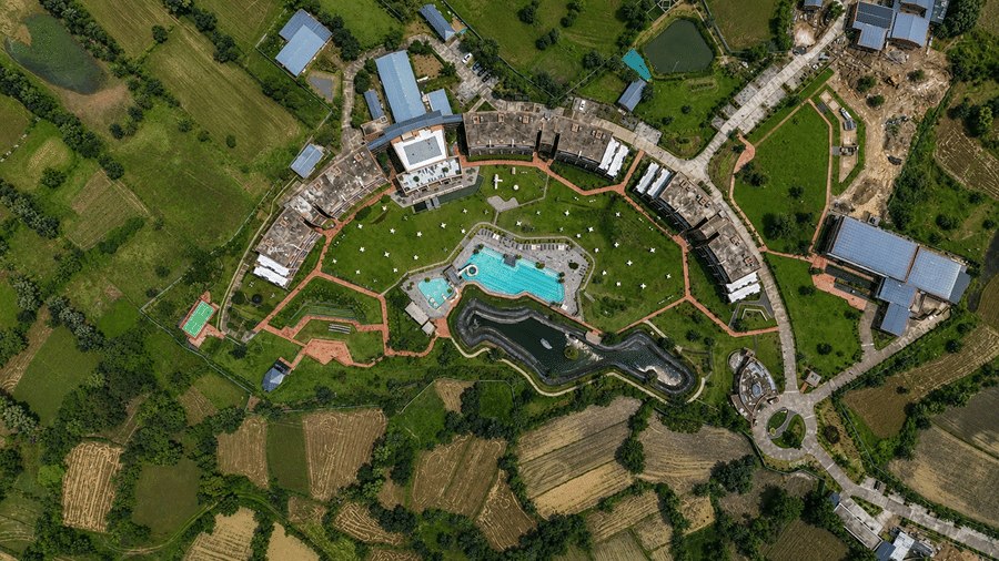A top-down aerial view of Hotel Sonar Bangla, Susunia featuring curved resort buildings, central pool, garden paths, and surrounding land.