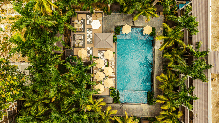 An aerial view of our swimming pool featuring lounges on 2 sides and surrounded by coconut palm trees | Hotel Sonar Bangla, Tarapith