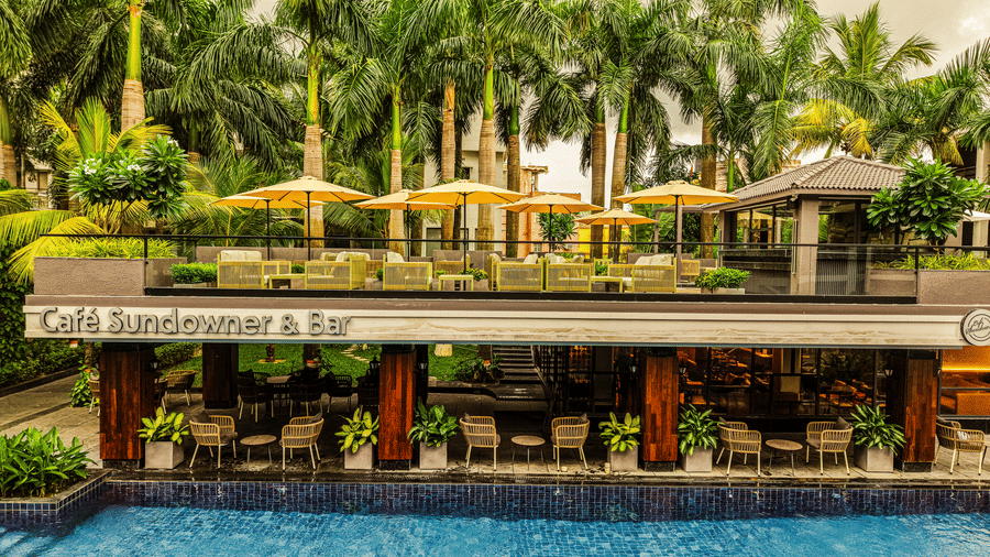 Sundowner Cafe featuring a duplex seating layout with an open first-floor dining deck covered by overhead sunshades and a ground-floor seating area located beside the swimming pool | Hotel Sonar Bangla, Tarapith
