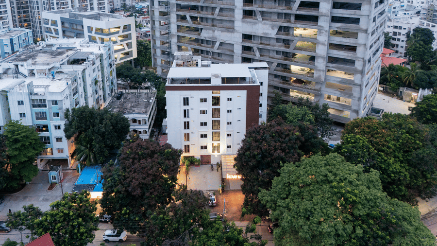 Aerial view of Kove Smart Stays, Hyderabad, seen at a partially dark hour, with the lights of the entryway turned on.