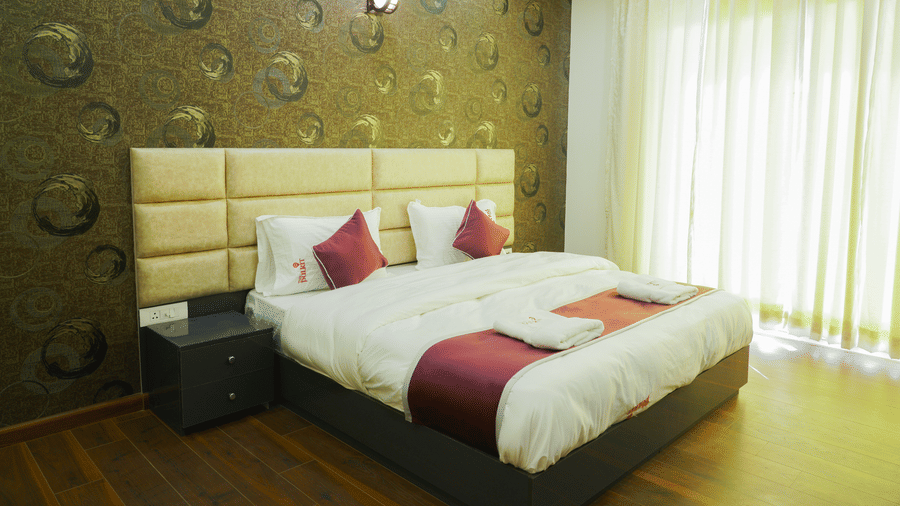 Bedroom of Lime Tree Hotel, Pulkit featuring dark wood flooring, a textured headboard, and maroon bedding.