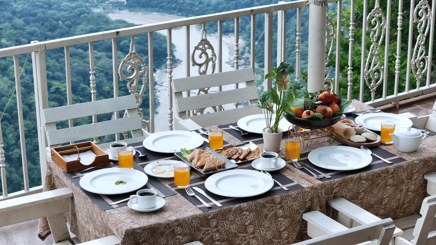 Several plates placed on a table with chairs beside on a rooftop at Neer Ganga.