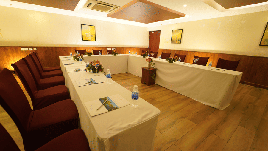 Tudor event hall at Ocean Spray Resort in Pondicherry featuring U-shaped seating area with table and chair. 