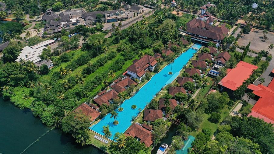 An aerial view of a swimming pool with rooms surrounded by trees - Rhythm Kumarakom