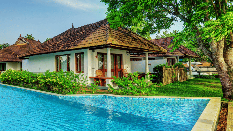 A swimming pool in front of the exterior of a room at Rhythm Kumarakom