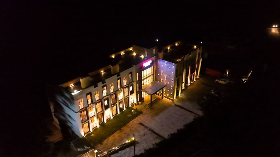 A brightly lit building is seen at night from an aerial perspective, showcasing its illuminated windows and exterior | Sukama Resort & Spa, Nainital