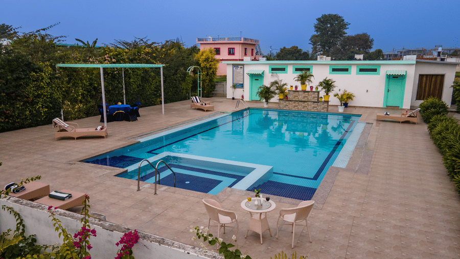 Swimming pool surrounded by a pavement  which has chairs, tables, lounger beds, and other seating areas at Vedikant Resorts The Mallard Corbett.