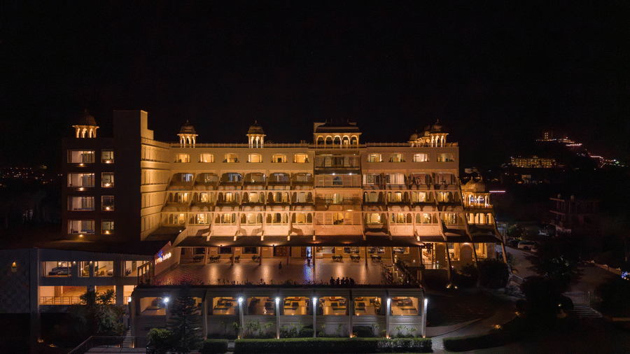 An evening view of Via Lakhela Lakeview Resort, showcasing the brightly lit facade, lakeside promenade, and glowing reflections on the water.