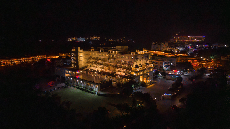 A night-time aerial view of Via Lakhela Lakeview Resort, showcasing the illuminated resort complex along the lakeshore, with warm lights reflecting on the surrounding water.