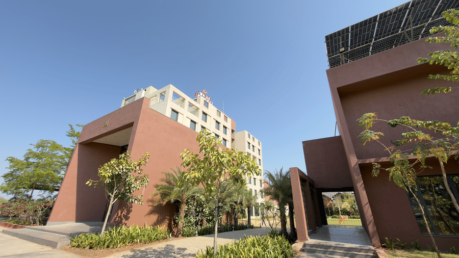 exterior of a Vinti Resort with reddish accents and some palm trees.