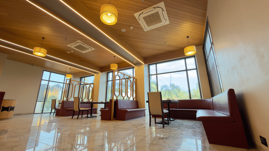 coffee shop in Vinti Resort with a  ceiling, lighting, red cushioned seating, and glass-topped tables.