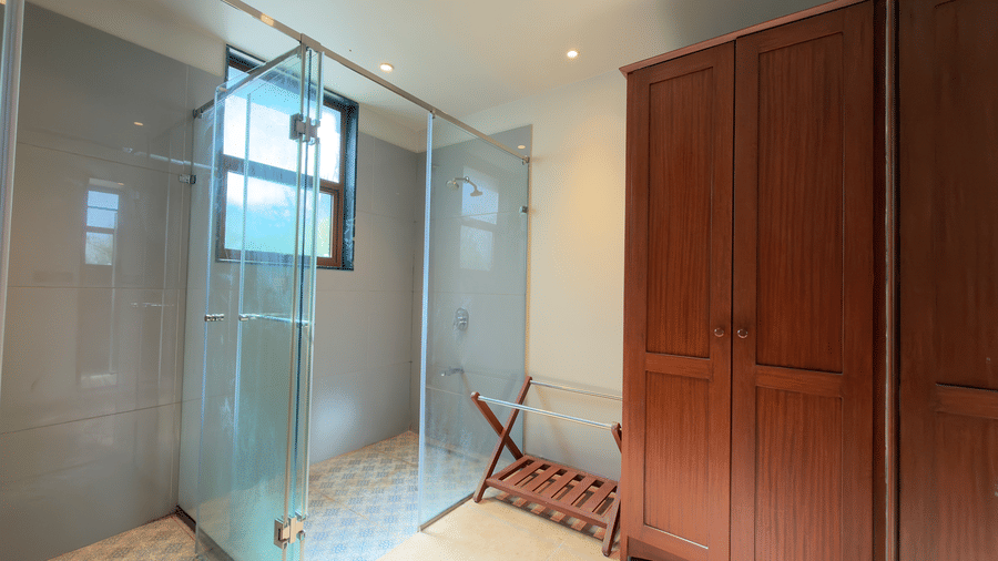 Bathroom of villa in Vinti Resort with dark  built-in wardrobes and a small window.
