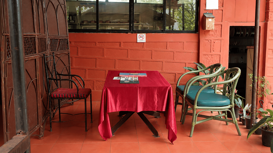 Covered outdoor seating area at Wind Chalet, featuring a square table with a tablecloth and two chairs on the chalet veranda.