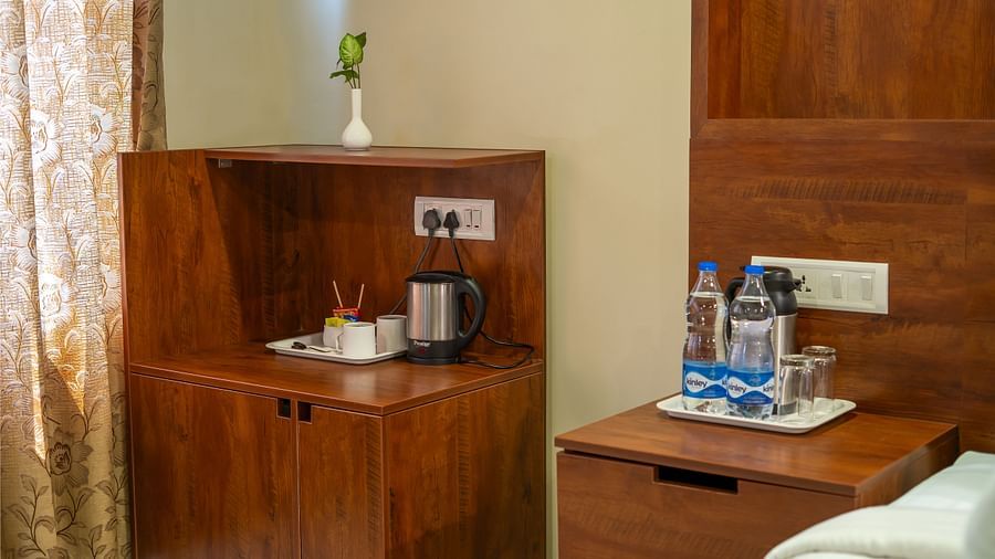 Superior Room displays a wooden cabinet, a side table, and a lamp | Woodstock Resorts, Coorg