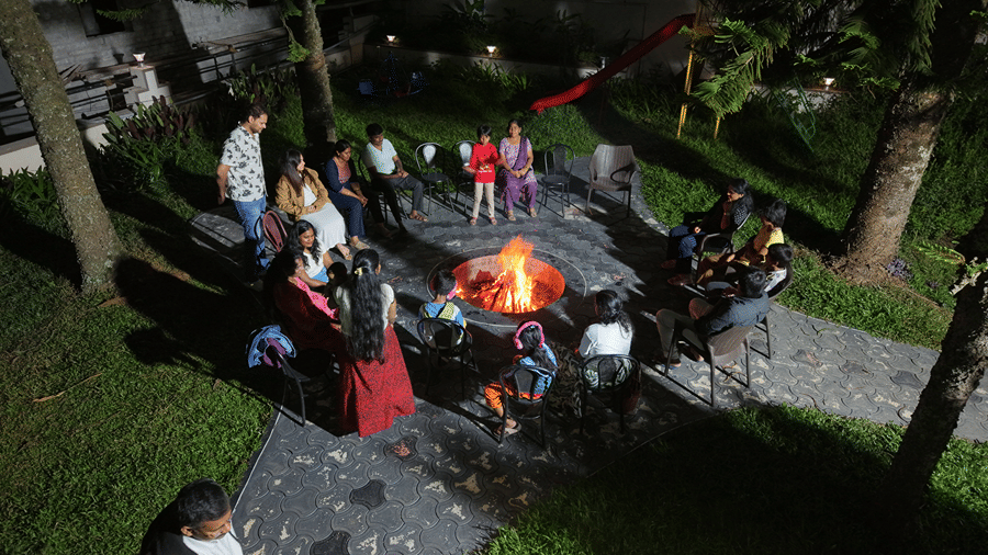 A bonfire set up made in an outdoor space with people enjoying by it. | WOW Naturefull Resorts, Yercaud