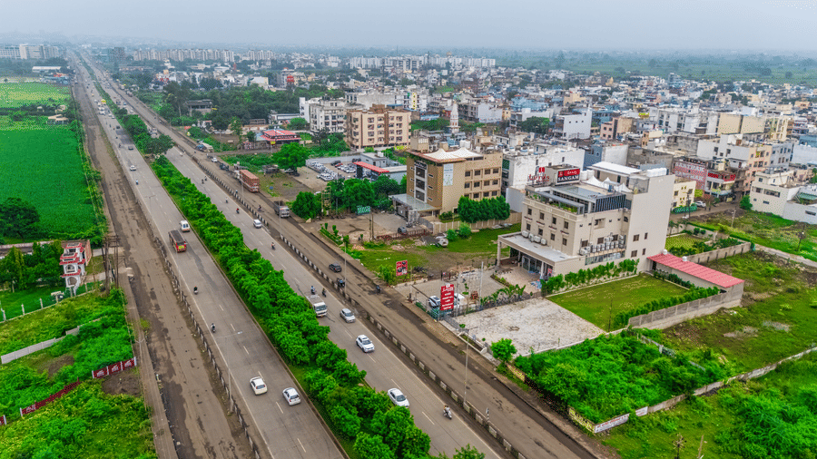 Aerial view near Lords Inn Sangam, Bhopal showing green fields, railway tracks, and the surrounding cityscape under an overcast sky.