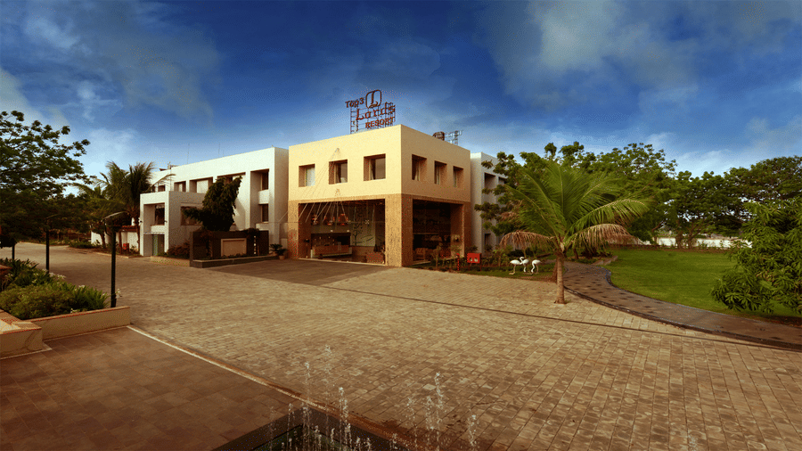 facade view of Top3 Lords Resort Bhavnagar with a spacious pathway and a lush green lawn area by side