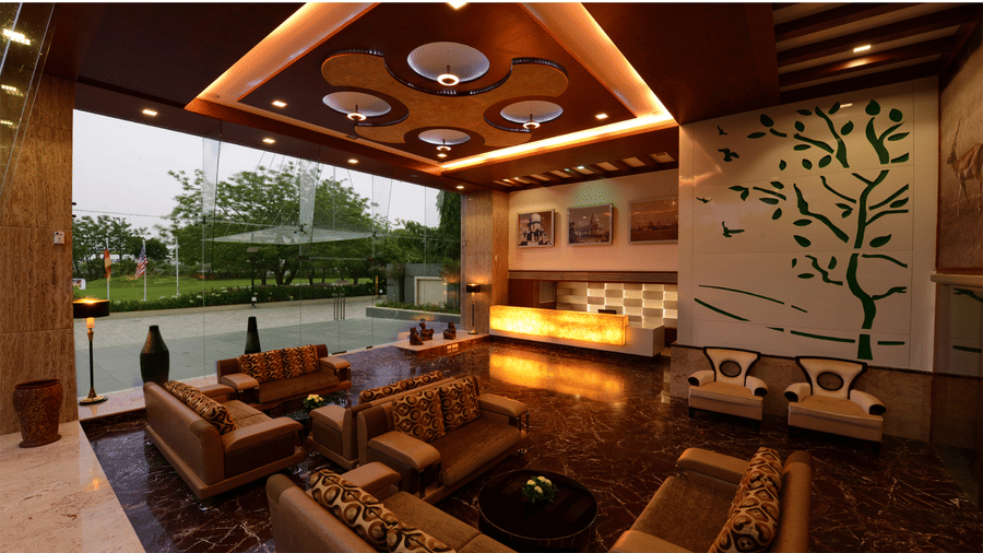 Top3 Lords Resort Bhavnagar hotels lobby area with a spacious seating area facing the reception  desk, with ceiling-to-floor glass doors