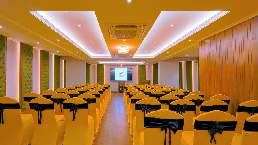  Presentation area in a conference hall with a screen and surrounding seating.