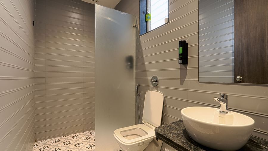 alt-text An image of a washroom featuring  sink and faucet,  mirror on the wall, and a commode on the side of the wash basin -  Magnus Fortune House, Magarpatta