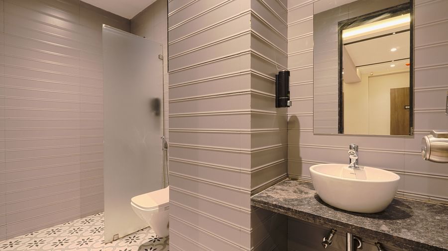 alt-text An image of a washroom featuring  sink and faucet,  mirror on the wall, and a commode on the side of the wash basin -  Magnus Fortune House, Magarpatta