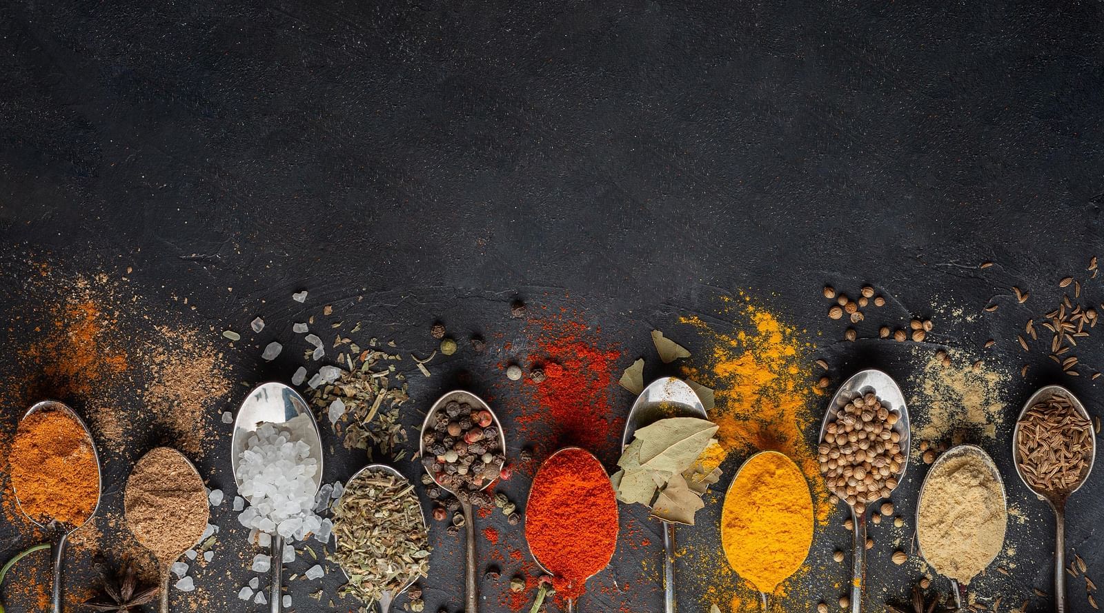 A creative display of various spices forming a splash effect on a black background.