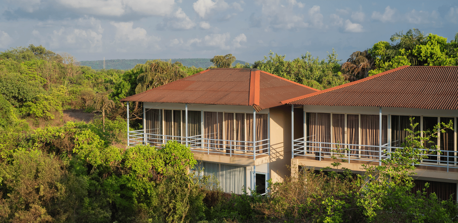 An aerial view of our accommodation buildings with orange-tiled balconies, surrounded by lush greenery - Perfectstayz Koko Maya