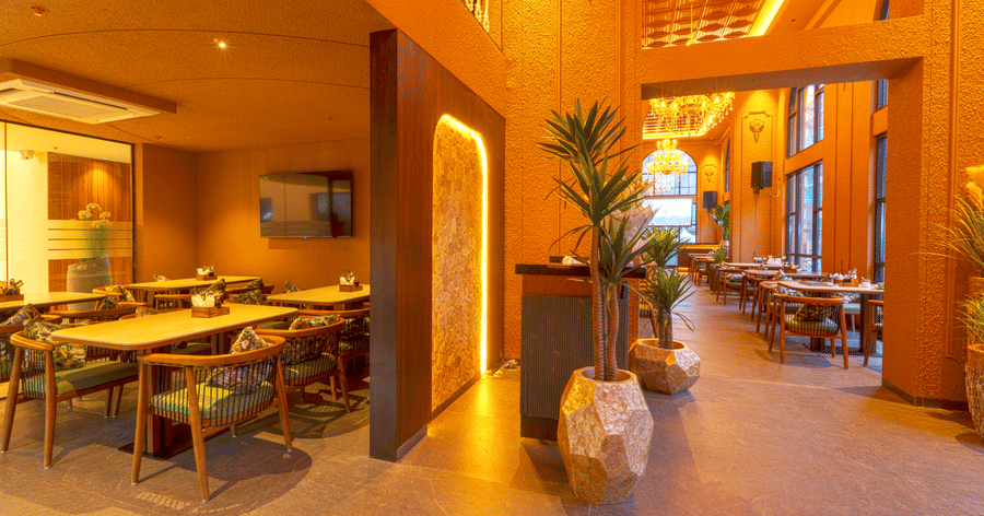 Stylish reception and indoor dining area at Cocobrisa featuring contemporary décor, elegant seating, decorative planters, warm lighting, and spacious interiors with high ceilings.