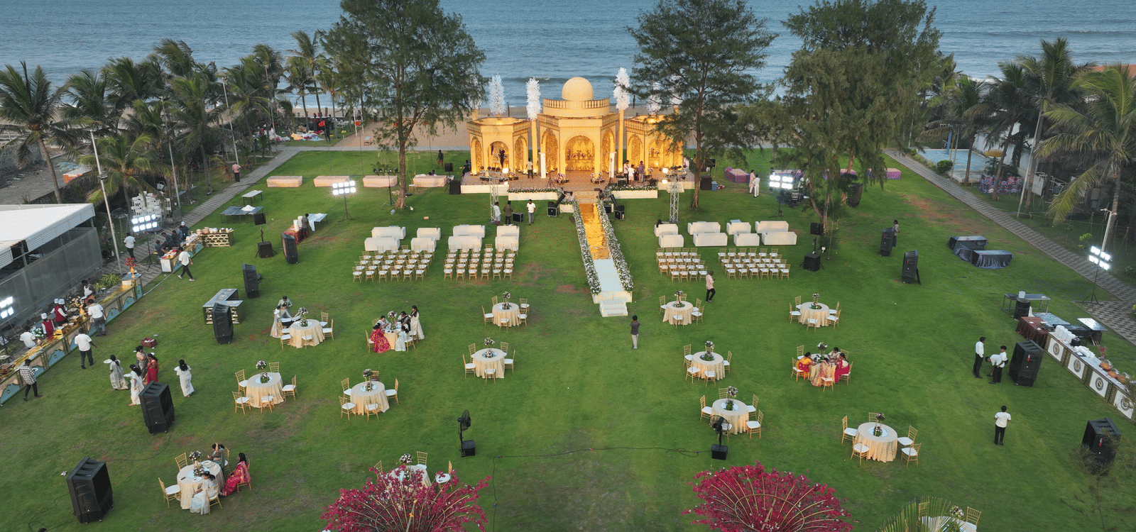 Aerial view of a beach-side wedding setup featuring a centre stage and cluster style seating arrangement - Grande Bay Resort & Spa, Mamallapuram