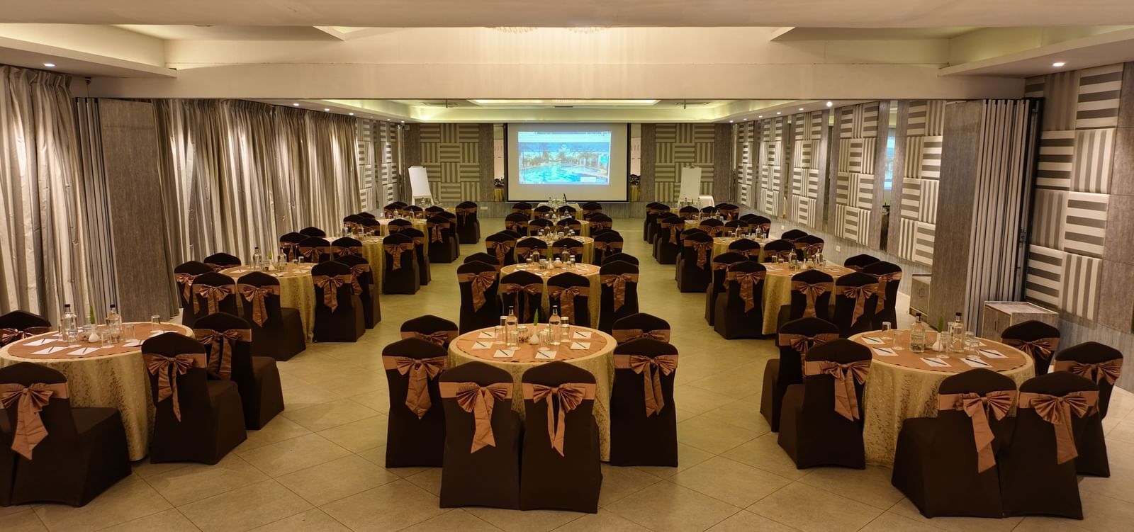 Banquet hall with brown chair covers arranged around round tables at Grande Bay Resort & Spa.