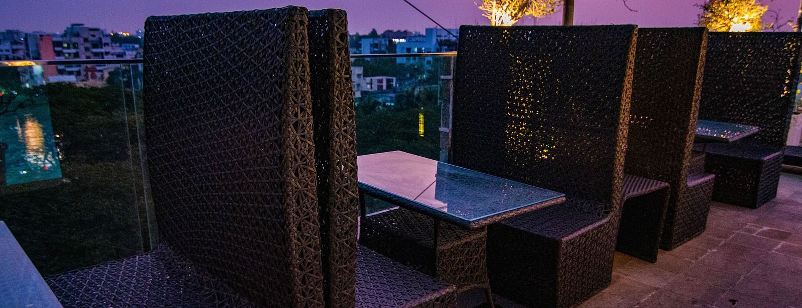 A dimly lit outdoor seating area with dark furniture and a small table at Hotel Ashok Nagpur.