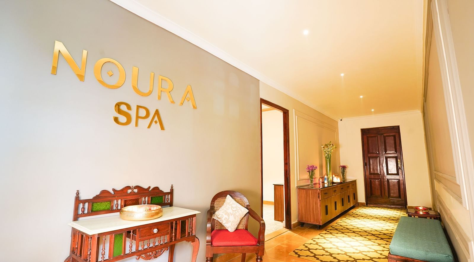 Image of the waiting area of Noura Spa at Saraca Hotel Lucknow featuring seating space and a Noura Spa written on the wall in golden colour