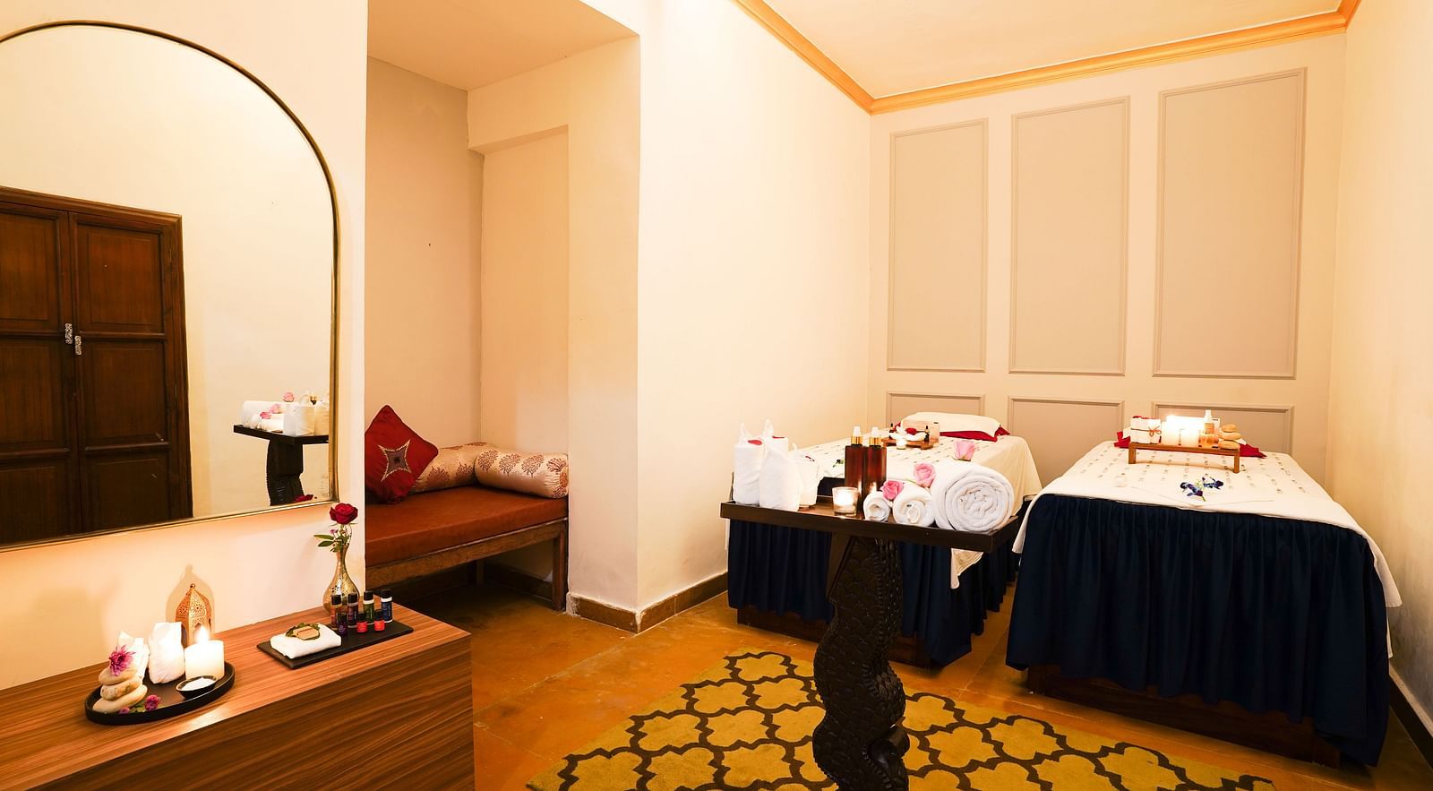 An image of the interior of a spa room featuring candles placed on a table and two spa beds next to each other