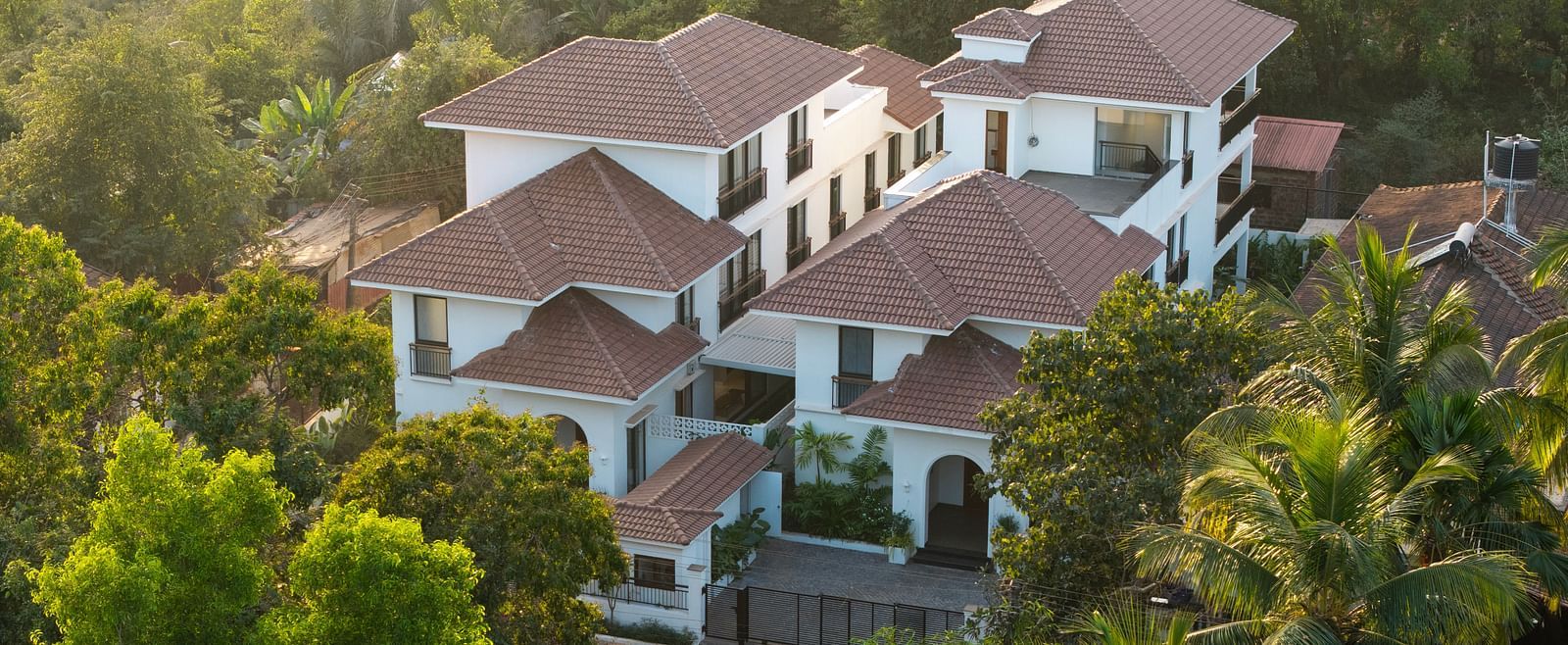 A bird's eye view of the property amidst trees with an impression of sunlight from the side  - BluSalzz Villas - Alocassia, Anjuna