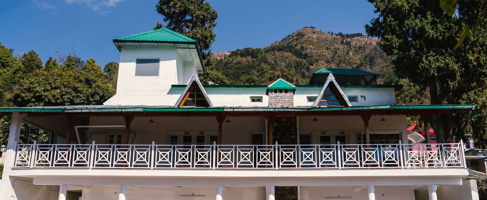 Facade of BluSalzz Villas - The Green Roof, Bhimtal, is set against a stunning backdrop of mountains and lush trees.