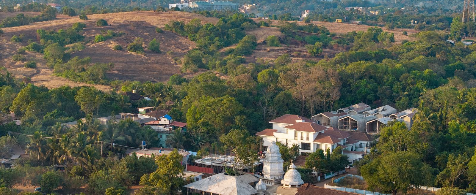 A panoramic view of a valley with rolling hills, scattered houses, and vibrant greenery under a clear sky - BluSalzz Villas - Alocassia, Anjuna