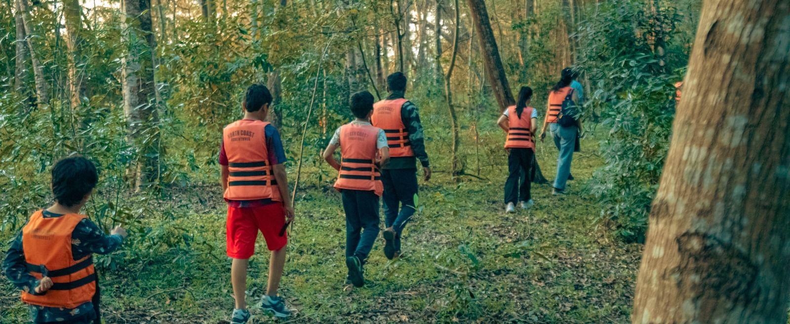 Group of guests wearing life jackets walking through a forest trail at Fireflies Resorts, Kabini.