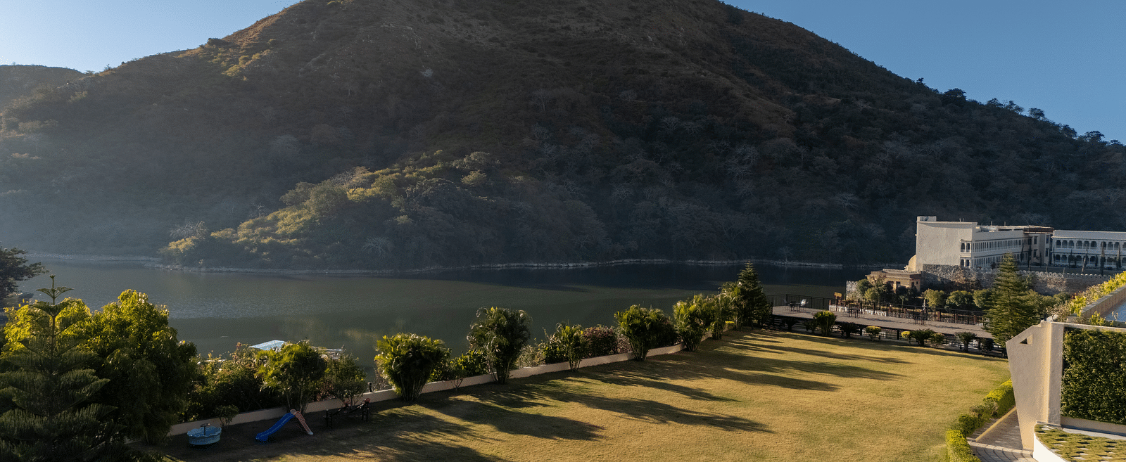Mountain with a winding road, trees, and water visible, sunny day - Via Lakhela Resort & Spa