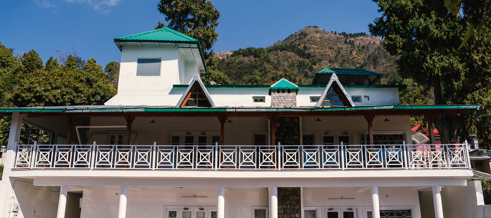 Facade of BluSalzz Villas - The Green Roof, Bhimtal, is set against a stunning backdrop of mountains and lush trees.