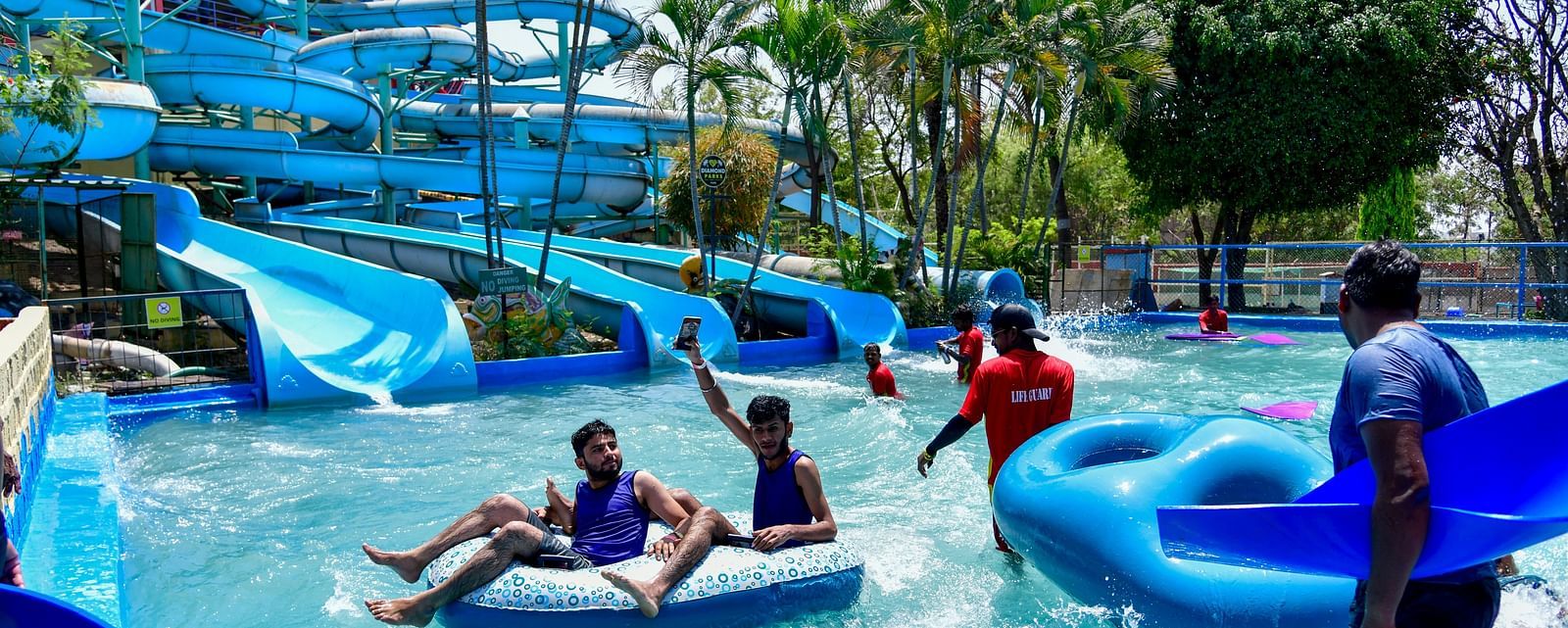Visitors enjoying a lazy river ride with large blue tubes at a water park | Diamond Parks, Pune 