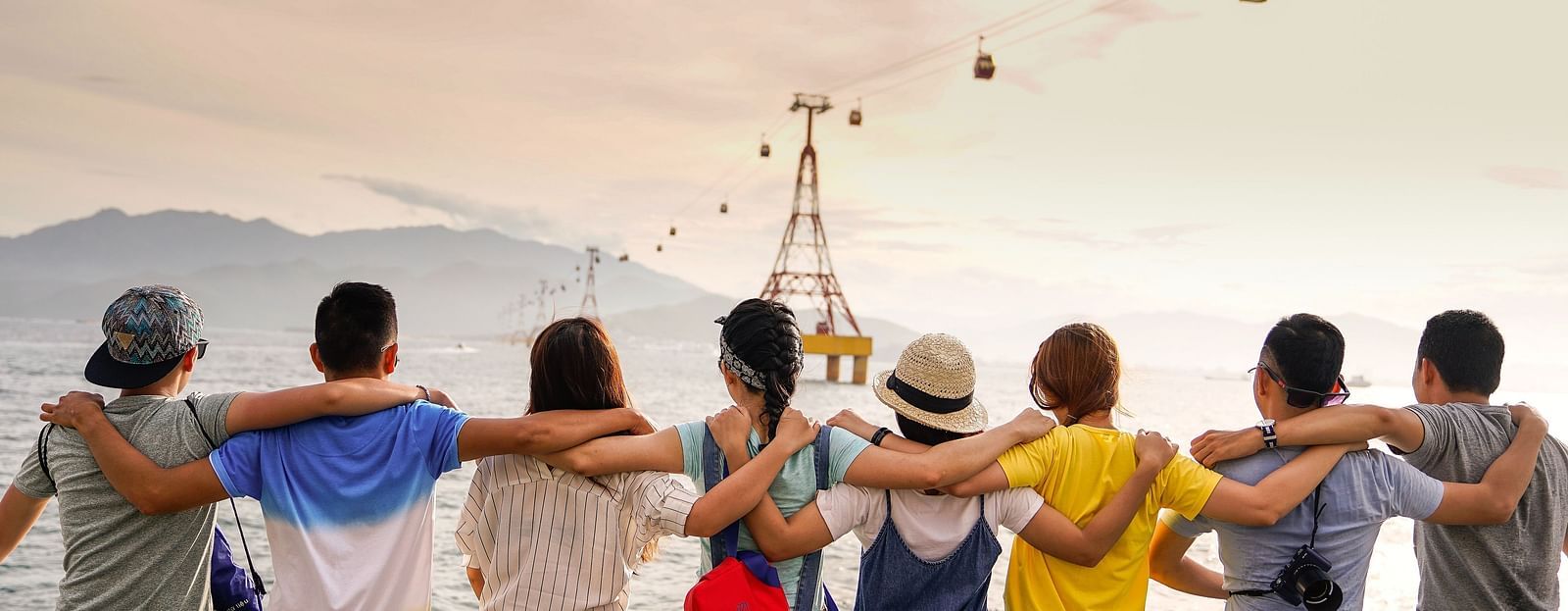 Friends sitting on a ledge near an ocean looking forward